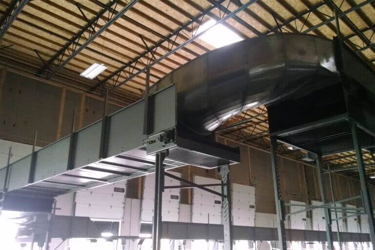 Elevated bulk conveyor system with black enclosure on steel supports in an industrial building.
