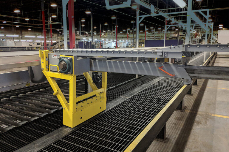 Yellow-framed roller conveyor bridge spanning the gap between loading dock and internal conveyor system.
