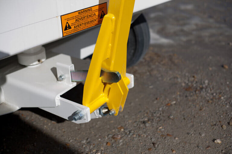 Yellow towbar in upright locked position on white baggage cart.