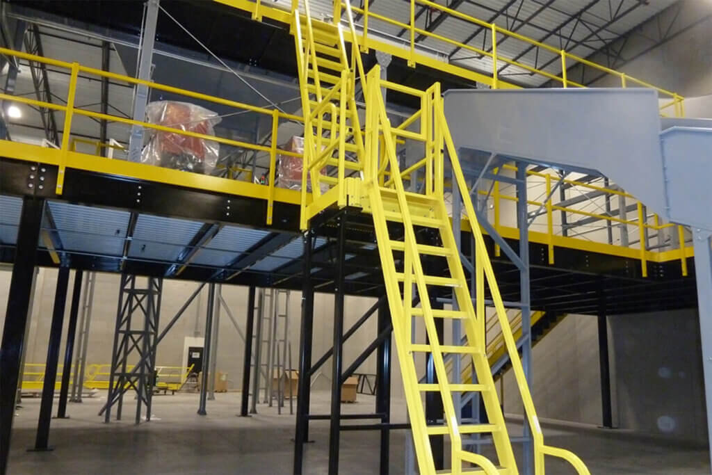 Yellow safety ladder providing access to elevated mezzanine platform with safety railings in an industrial facility.