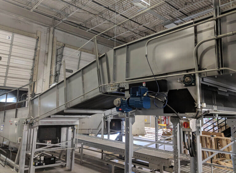 Large industrial conveyor system with multiple levels and blue motor components in warehouse setting.