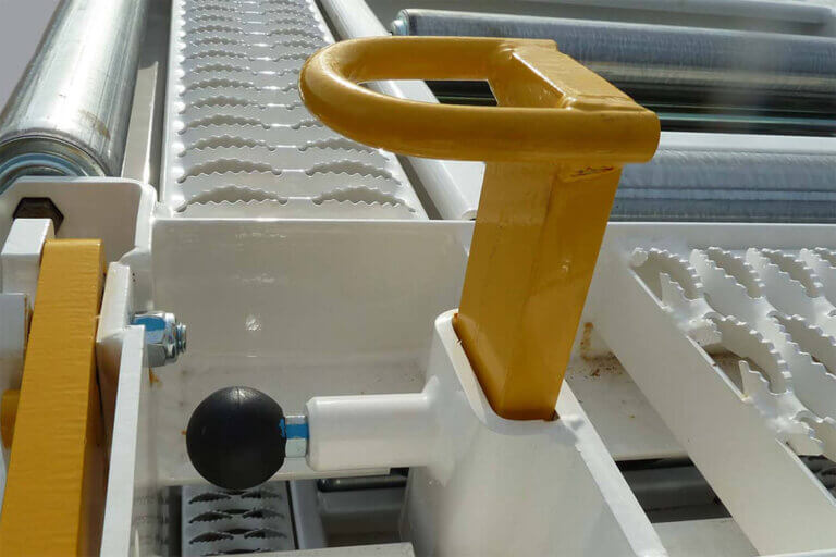 Yellow pallet stop handle with black knob mounted on metal grated cargo trailer floor.