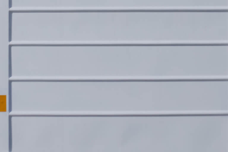 Close-up of white powder-coated metal slats with horizontal ridges.