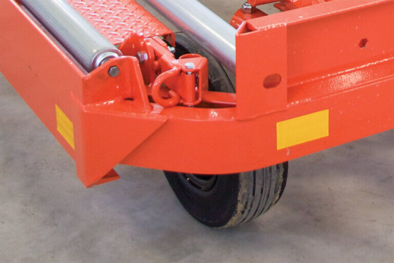 Close-up of red industrial container dolly showing wheel assembly with curved radius corner and safety markings.