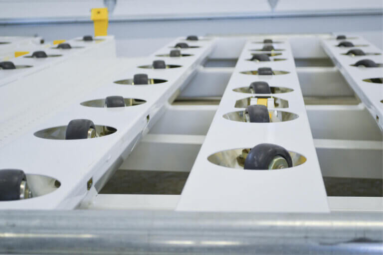 White cargo platform with multiple black sealed caster wheels embedded in circular openings for smooth movement.