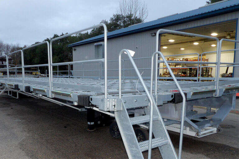 Elevated metal loading platform with safety railings and access stairs outside industrial building.
