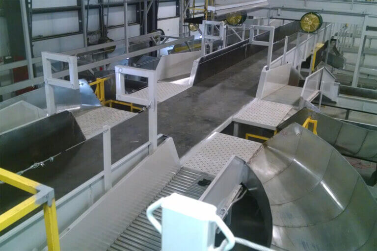 Industrial material sorting system with elevated walkways, conveyor belts, and sorting chutes in a manufacturing facility.
