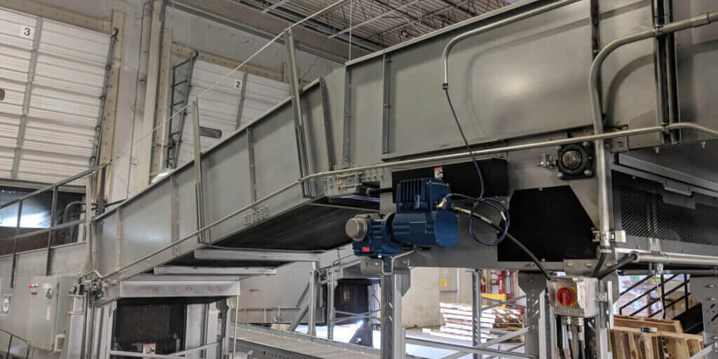 Large industrial conveyor system with multiple levels and blue motor components in warehouse setting.